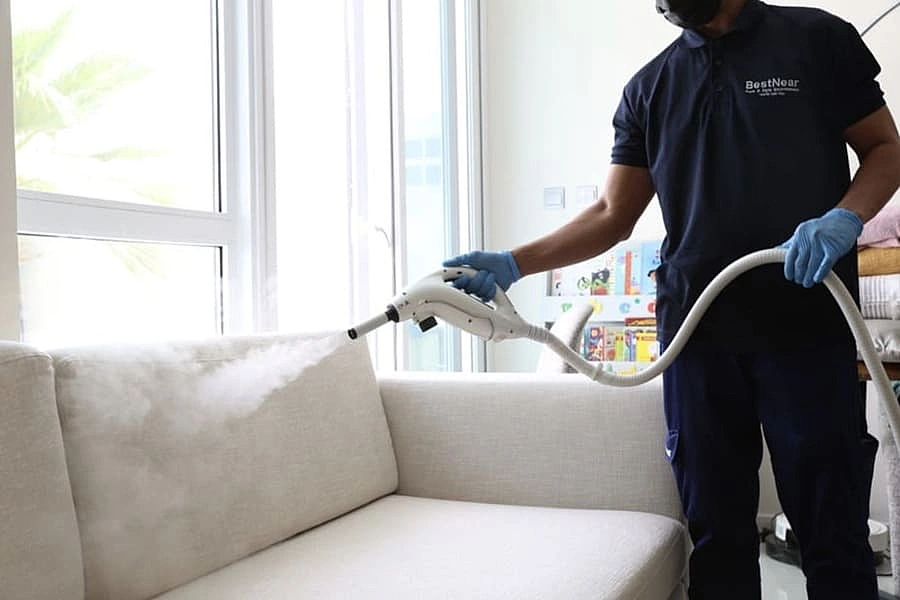 A BestNear technician cleaning a light-coloured sofa